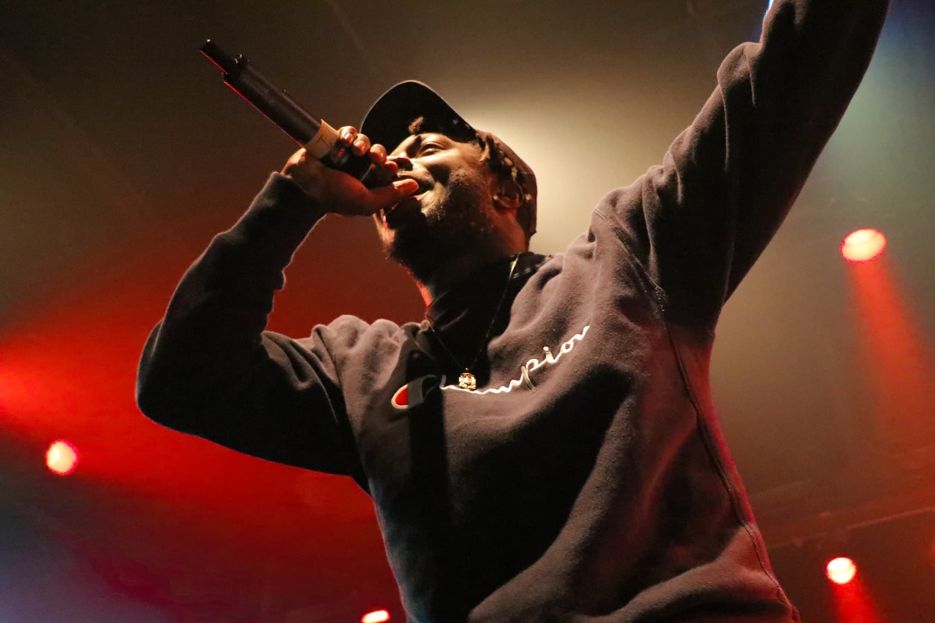 A rapper from a low view performing into a microphone at a show.